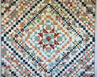 May include: A quilt with a geometric pattern in shades of gray, white, orange, and red. The quilt is made up of small squares and triangles, and it features a large star in the center.