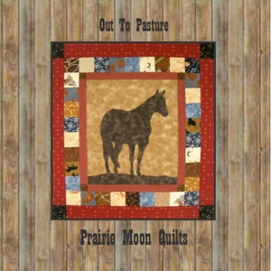 May include: A quilt with a red border and a brown horse silhouette in the center. The quilt is made of various fabrics with different patterns. The text "Out To Pasture" is at the top and "Prairie Moon Quilts" is at the bottom.