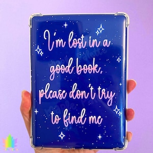 May include: A blue e-reader case with a starry design and the quote, "I'm lost in a good book, please don't try to find me," in pink script. The case has clear corner protectors.