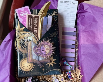 Op de afbeelding: Een cadeaupakket gevuld met leesartikelen. Inclusief een decoratieve envelop met een zon- en maanontwerp, een leeslijst, bladwijzers, een gouden veer en een vlinderbedel. De envelop leest "ROMANCE BOOK" en "Powered by book and coffee."