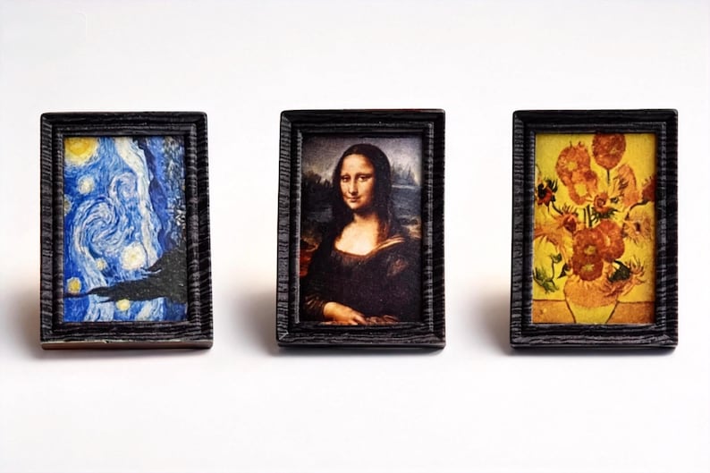 May include: Three miniature framed art prints. The prints feature famous artworks: Van Gogh's "Starry Night", the Mona Lisa, and Van Gogh's "Sunflowers". The frames are dark wood with a textured appearance.