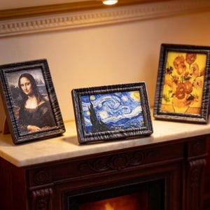 May include: Miniature framed art prints featuring famous paintings. The set includes a portrait of the Mona Lisa, Van Gogh's "Starry Night", and a floral still life. The frames are dark with a textured appearance, and the art is displayed on a miniature fireplace mantel.