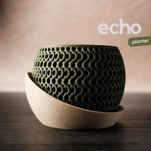 Puede incluir: Un macetero verde con un patrón texturizado ondulado. El macetero está hecho de un material duradero y tiene una base beige. El macetero está etiquetado como "echo planter".