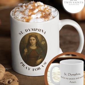 May include: White ceramic mug featuring an image of St. Dymphna, with text that reads "St. Dymphna, Pray for us!" The mug is filled with a beverage topped with whipped cream and cinnamon. The Twin Saints Inspirations logo is visible.