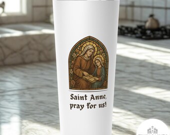 May include: A white stainless steel travel mug with a stained-glass style illustration of Saint Anne teaching a young girl. The image is framed by a gold border with floral accents. Text reads "Saint Anne, pray for us!"