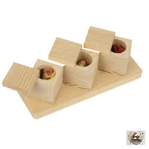 May include: A wooden serving tray with four small, square wooden boxes, each with a circular opening and a removable lid. The boxes contain dried fruits and nuts. The tray and boxes are made of light-colored wood.