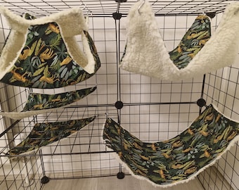 May include: A selection of pet hammocks and triangular beds. The items display a dark green fabric with a jungle pattern of leaves and cheetahs, complemented by a soft, cream-coloured lining. The accessories are designed to hang inside a cage.
