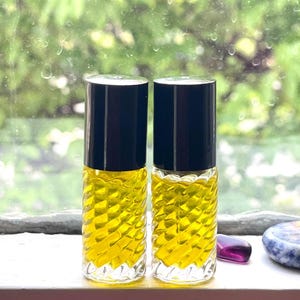 Puede incluir: Dos botellas de vidrio transparente con tapones negros llenas de un líquido amarillo. Las botellas tienen un diseño texturizado.