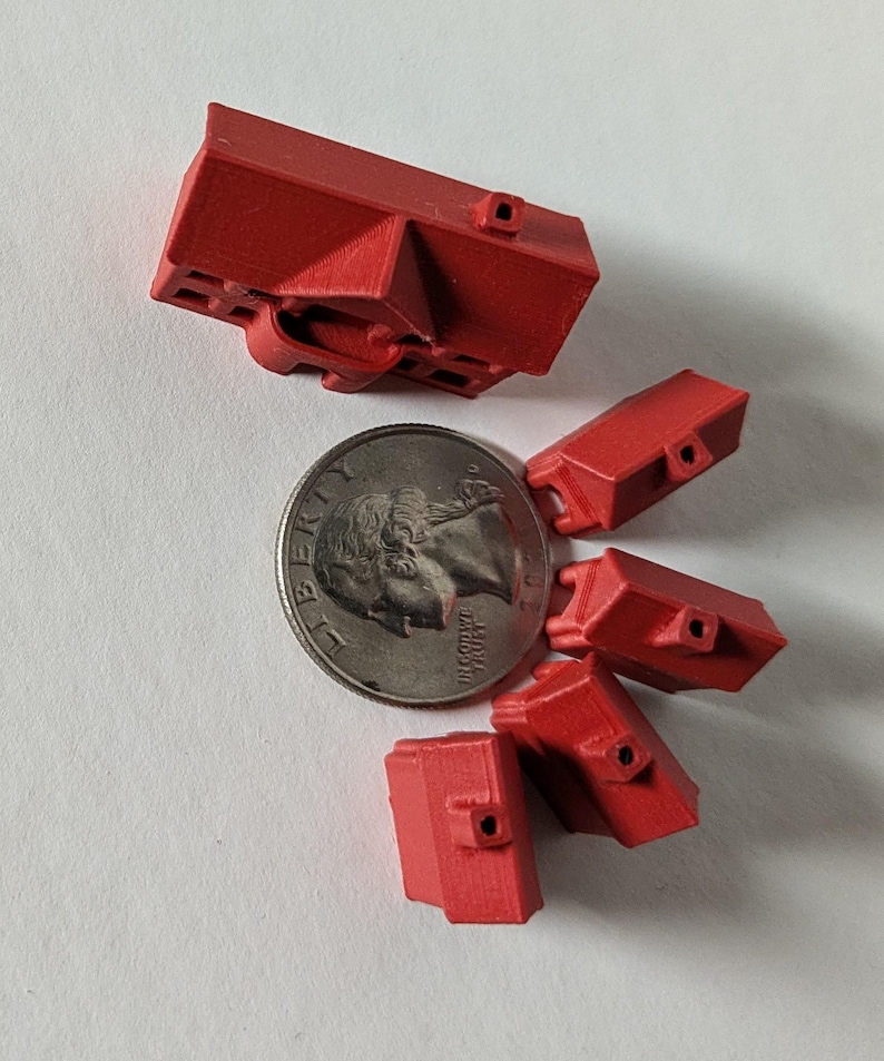 Puede incluir: Cinco casas rojas en miniatura sobre un fondo blanco. Las casas son aproximadamente del tama&ntilde;o de una moneda de 25 centavos de d&oacute;lar estadounidense.