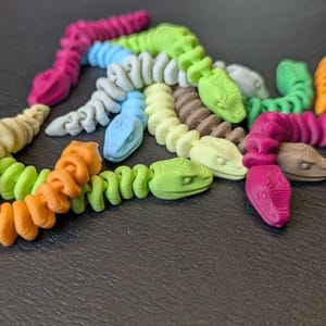 May include: A white ceramic mug with a black handle and the text "But First, Coffee" in a bold, black font. The mug is set against a blurred background, suggesting a cozy setting.