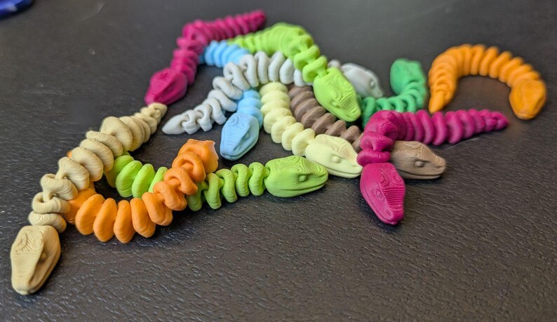 May include: A white ceramic mug with a black handle and the text "But First, Coffee" in a bold, black font. The mug is set against a blurred background, suggesting a cozy setting.