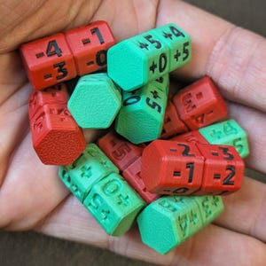 May include: A handful of red and green hexagonal dice with black numbers and plus signs. The dice are 3D-printed and feature numbers like -4, -1, +5, and +0. The dice are for a tabletop game.
