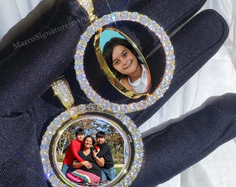 May include: Two gold-tone pendants with a round, clear, diamond-like stone encrusted frame. Each frame holds a photo of a family. The pendant on the left has a photo of a family of three, and the pendant on the right has a photo of a young child.