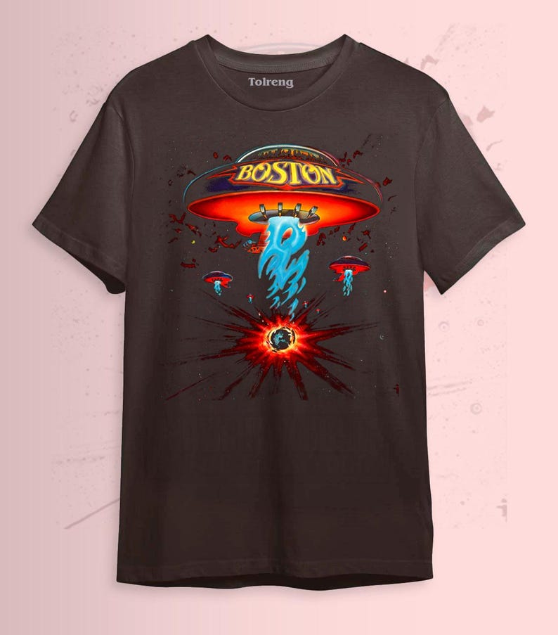 May include: Dark brown t-shirt featuring a graphic design with the word "BOSTON" in gold lettering on a red and orange UFO. The design includes blue flames and smaller UFOs, with a burst of red and black radiating from a central point.