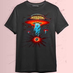 May include: Black t-shirt featuring a graphic design with the word "BOSTON" in gold lettering above a red and orange UFO. The design includes blue flames and smaller UFOs, with a burst of red and black radiating from a central point.