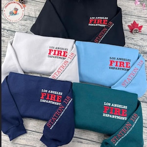 Könnte beinhalten: Eine Auswahl an Crewneck-Sweatshirts in verschiedenen Farben, darunter Schwarz, Weiß, Hellblau, Marineblau und Teal. Jedes Sweatshirt zeigt den Text "LOS ANGELES FIRE DEPARTMENT STATION 118" in Rot und Weiß.
