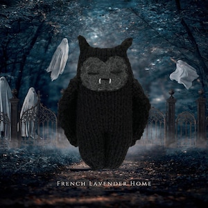 May include: A black knitted bat plush toy with a dark grey face, closed eyes, and two small white fangs. The bat has pointed ears and textured wings, with the text FRENCH LAVENDER HOME printed in white at the bottom of the image.