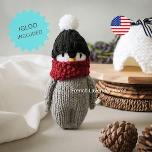 Peut inclure: Une poupée pingouin tricotée à la main avec un corps gris, un bonnet noir à pompon blanc et une écharpe rouge. La poupée a un bec jaune et des yeux noirs. Un graphique bleu clair en forme d'étoile indique IGLOO INCLUDED, et le texte French Lavender Home.