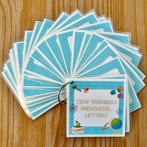 May include: A set of blue and white alphabet flash cards with a title card that reads "Tiny Thinkers Preschool Letters". The title card features a globe, a book, pencils, scissors, and building blocks.