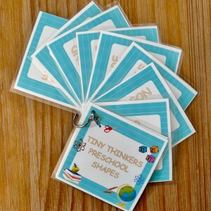 May include: A set of blue and white flashcards with a ring binder. The flashcards have the title "Tiny Thinkers Preschool Shapes".