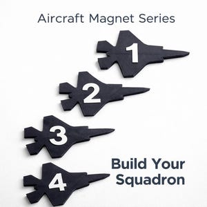 Puede incluir: Cuatro imanes negros con forma de avión, numerados del 1 al 4 en blanco. También se ve el texto "Aircraft Magnet Series" y "Build Your Squadron". Los imanes están dispuestos verticalmente sobre un fondo blanco.