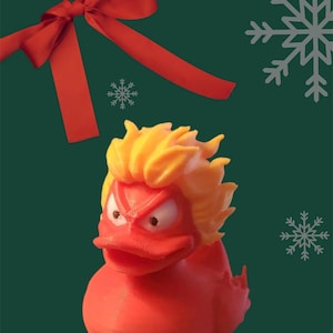 May include: A red rubber duck with a yellow flame-like hairdo and an angry expression. The duck is a Christmas themed toy.