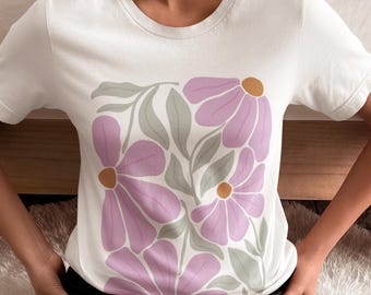 May include: White t-shirt featuring a floral design. The design includes large pink flowers with orange centers and gray leaves. The shirt is a crew neck style and appears to be made of cotton.