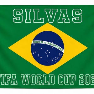 May include: A rectangular flag featuring the green, yellow, and blue Brazilian flag design. The word SILVAS is printed in white block letters at the top, and the text FIFA WORLD CUP 202 is printed in white block letters at the bottom.