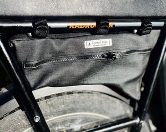 Puede incluir: Bolsa negra para portabultos de bicicleta con cremallera y una pequeña etiqueta que dice "Conrad Bags Handmade in the USA".