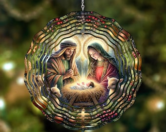 May include: A circular metal wind spinner featuring a colorful nativity scene. The design depicts a man and a woman kneeling beside a baby in a manger, surrounded by lambs. The outer edges of the spinner have a wavy, layered metal construction.