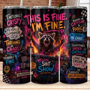 May include: A cylindrical tumbler featuring a vibrant, chaotic graphic print of a raccoon emerging from a dumpster. The design includes neon-colored text such as THIS IS FINE, I'M FINE, EMOTIONALLY CRISPY, and WELCOME TO THE SHIT SHOW, with a straw.