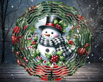 May include: A circular metal wind spinner featuring a central illustration of a snowman wearing a black top hat and a black and white checkered scarf. The design includes green holly leaves, bright red berries, and a red bow at the bottom.