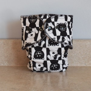 May include: Black and white cloth diaper cover with a checkered pattern featuring alternating images of dogs and cats.