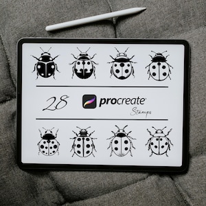 May include: A digital tablet shows eight black and white ladybug designs with different spot patterns. The tablet also displays the number "28", the Procreate logo, and the word "Stamps". A white stylus is positioned above the tablet.
