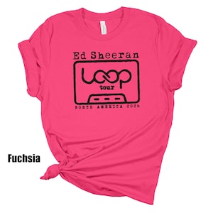 May include: A fuchsia short-sleeved t-shirt featuring a black graphic print on the chest. The design includes the text Ed Sheeran, the word loop, the word tour, and the text NORTH AMERICA 2026, all centered within a rectangular cassette tape outline.