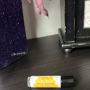 May include: A yellow and black lip balm tube with the text "G's BEE BALM LIP BALM" on the label.