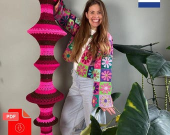 May include: A tall, cylindrical hanging crochet decoration featuring alternating horizontal bands of vibrant hot pink and dark brown yarn. The structure has multiple flared, circular tiers and ends with a dense fringe of dark brown yarn at the base.