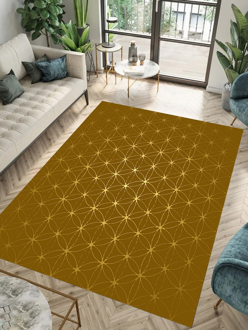 May include: A gold area rug with a geometric pattern of overlapping circles and stars. The rug has a brown background and gold accents.