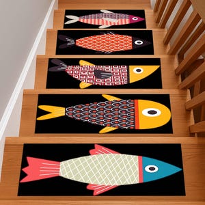 Pode incluir: Cinco tapetes retangulares para degraus com fundo preto, cada um apresentando um peixe estilizado. Os peixes exibem vários padrões geométricos e cores, incluindo vermelho, laranja, amarelo e azul, com barbatanas e olhos circulares.