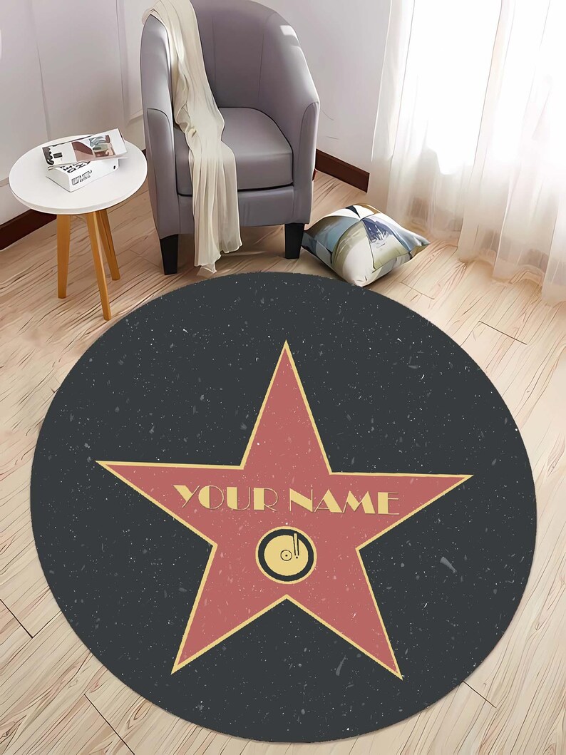 May include: A round black and red rug with a large red star in the center. The star has a gold outline and the words "YOUR NAME" written on it. The rug has a speckled texture.