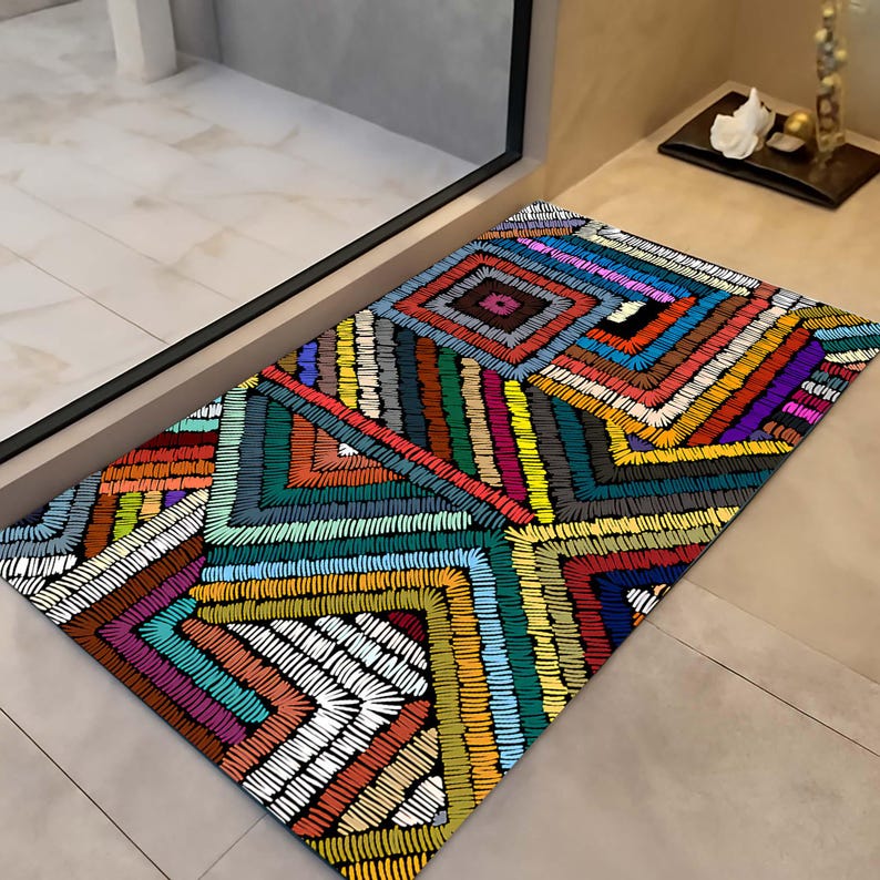 May include: Rectangular doormat with a vibrant, geometric design. The mat features a repeating pattern of colourful, stitched lines in shades of red, blue, green, yellow, and purple. The design creates a textured, eye-catching appearance, suitable for an entryway.