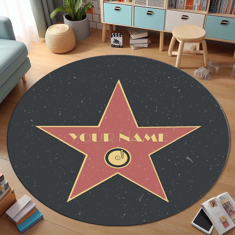 May include: A round, black and gray area rug with a red star in the center. The star has a yellow outline and the words "YOUR NAME" written in yellow across the center.
