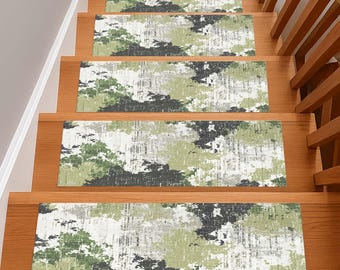 May include: Set of five stair treads with a green, gray, and black abstract pattern. The treads are rectangular and placed on wooden stairs. The design resembles a watercolor or brushstroke effect, adding a decorative element to the staircase.