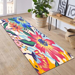 May include: A colourful floral runner rug with a white background. The rug features large pink, yellow, and blue flowers with green leaves. The rug is perfect for adding a touch of colour and style to any room.