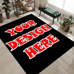May include: Black rectangular rug featuring the text "YOUR DESIGN HERE" in large red letters with a white outline. The rug is placed on a light wood floor, with a green bench and plants in the background.
