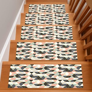 May include: Stair treads with a geometric pattern in shades of pink, gray, black, and white, accented with gold lines. The treads are installed on wooden stairs, offering a decorative and functional element for home decor.