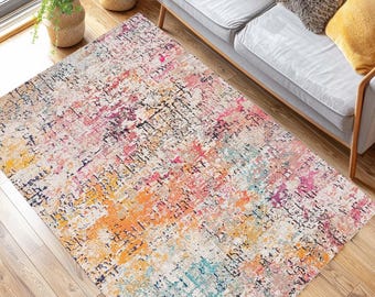 May include: A rectangular area rug with a distressed, abstract design. The rug features a blend of colors, including orange, pink, blue, and purple, with a cream-colored background. The rug is placed on a hardwood floor.