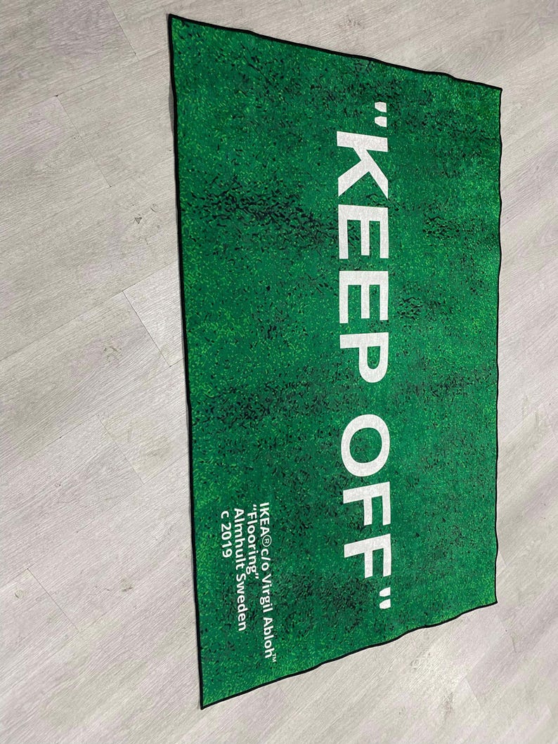 Puede incluir: Una alfombra verde con el texto "KEEP OFF" en letras blancas. La alfombra est&aacute; hecha por IKEA en colaboraci&oacute;n con Virgil Abloh y est&aacute; etiquetada como "Flooring" con el a&ntilde;o 2019.