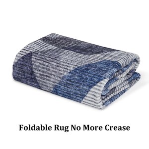 K&ouml;nnte beinhalten: Ein gefalteter blauer und wei&szlig;er Teppich mit geometrischem Muster. Der Teppich besteht aus einem weichen, pl&uuml;schigen Material und ist so konzipiert, dass er faltbar ist, was ihn einfach zu verstauen und zu transportieren macht. Der Text "Foldable Rug No More Crease" ist auf dem Bild sichtbar.