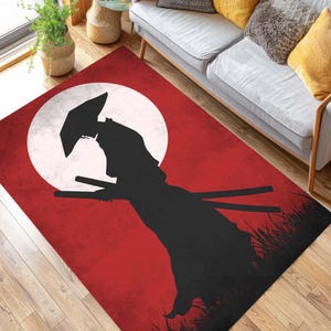 May include: A rectangular rug with a samurai warrior silhouette against a red backdrop and a white moon. The rug has a distressed appearance, with a black grass design at the bottom. The rug is suitable for a living room.